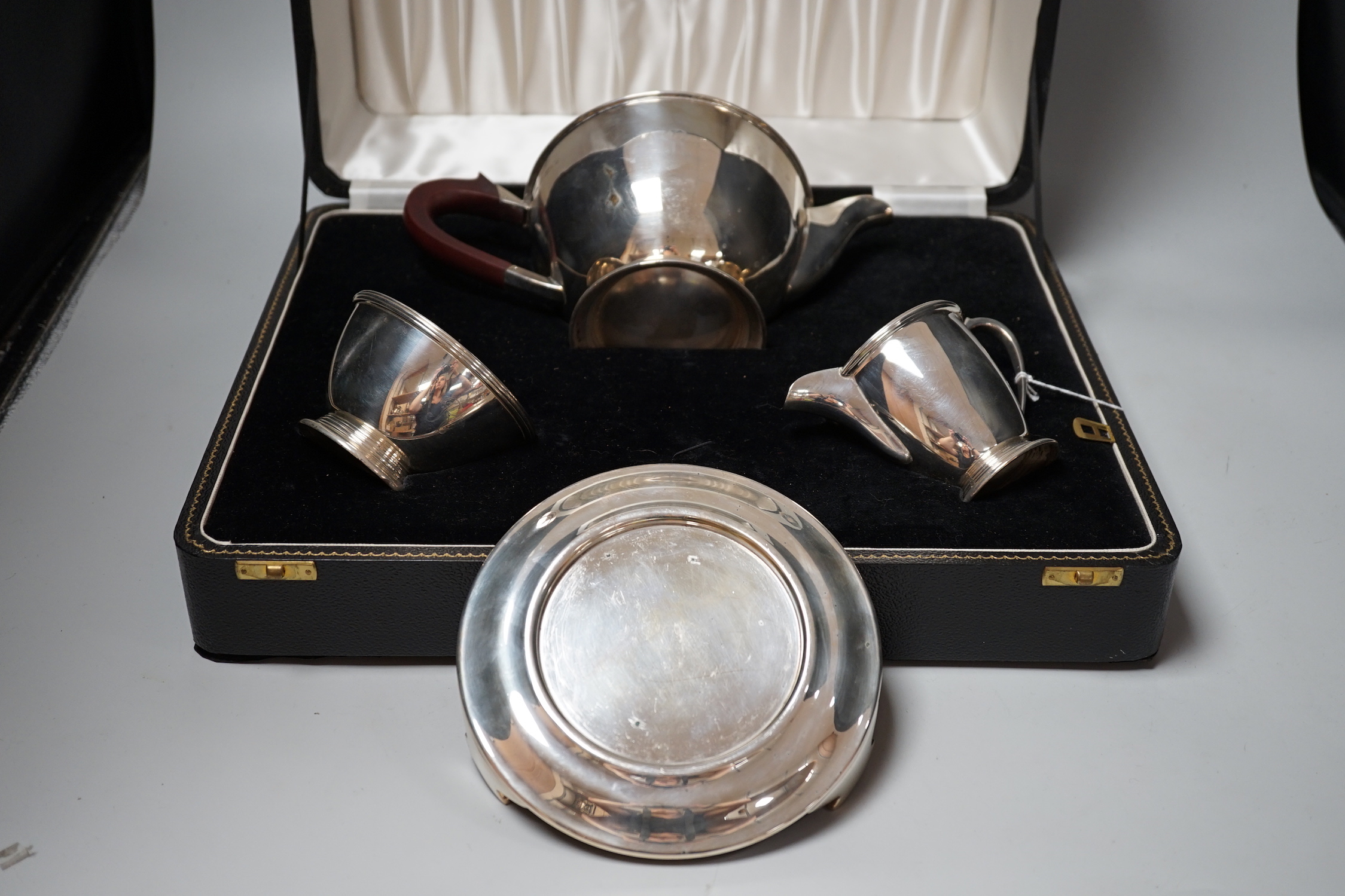 A cased Elizabeth II three piece silver tea set, Adie Bros. Birmingham, 1960, gross 23.7oz, with a plated teapot stand.